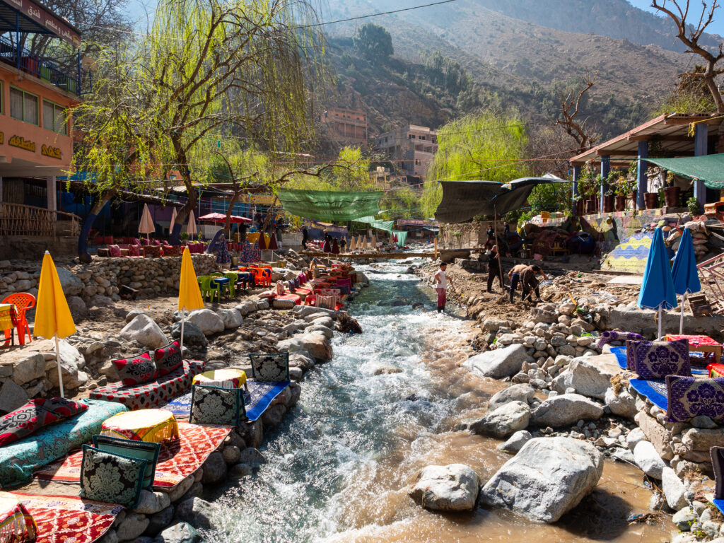 Outdoor riverside tables and eating spaces at colourful waterside restaurants in the Ourika Valley in the foothills of the Atlas Mountains in Morocco, North Africa.